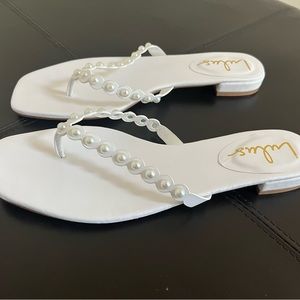 White flip flops with pearls on the straps.